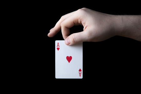 human hand holding the ace of hearts on a black backgroundの写真素材