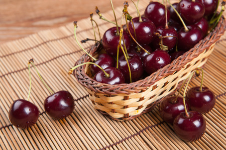 Ripe sweet cherry in the basket on a bamboo napkinの写真素材