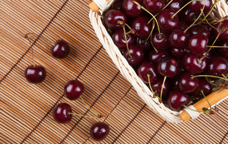 Ripe sweet cherry in the basket on a bamboo napkinの写真素材
