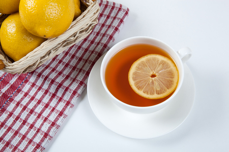 Still life of fresh lemons in a basket and a cup of tea close upの写真素材
