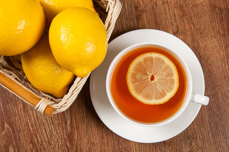 Still life of fresh lemons in a basket and a cup of tea close upの写真素材
