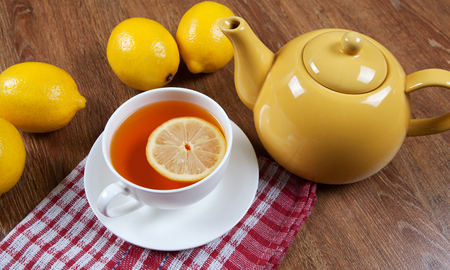 Still life of fresh lemons on a wooden table with cup of tea close upの写真素材