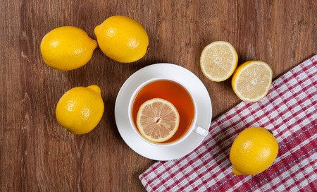 Still life of fresh lemons on a wooden table with cup of tea close upの写真素材