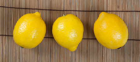 Still life of three fresh lemons on a bamboo napkin close upの写真素材