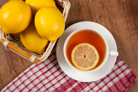 Still life of fresh lemons in a basket and a cup of tea close upの写真素材
