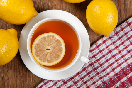 Still life of fresh lemons on a wooden table with cup of tea close upの写真素材