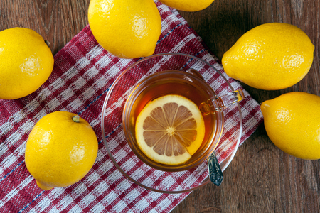 Still life of fresh lemons on a wooden table with cup of tea close upの写真素材