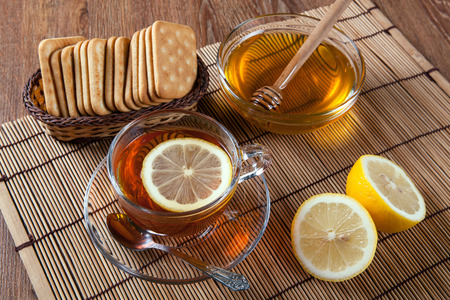 Still life of fresh lemons on a bamboo napkin with cup of tea close upの写真素材