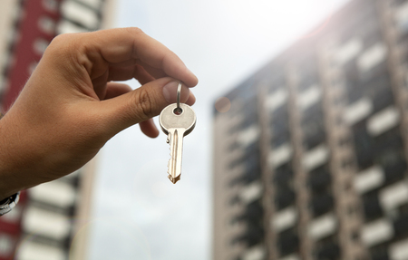 A man's hand holds the keys on the background of new buildingsの写真素材