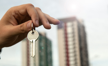 A man's hand holds the keys on the background of new buildingsの写真素材