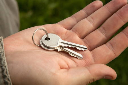 the owner of the apartment holds the keys in his handの写真素材