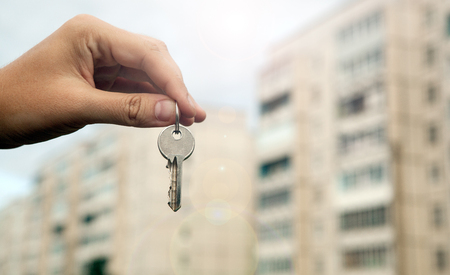 A man's hand holds the keys on the background of new buildingsの写真素材