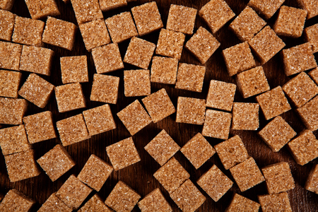 background of cubes of brown sugar on a wooden table close upの写真素材