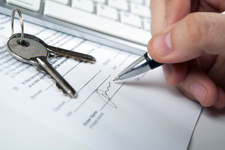 apartment keys, mortgage loan document and human hand and a keyboardの写真素材