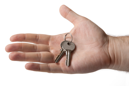 the owner of the apartment holds the keys in his handの写真素材