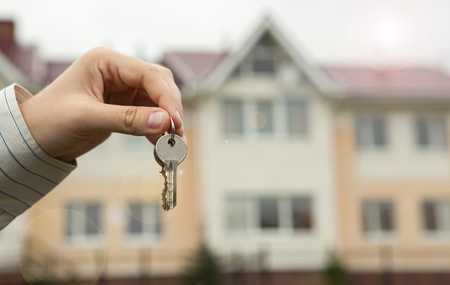 A man's hand holds the keys on the background of new buildingsの写真素材
