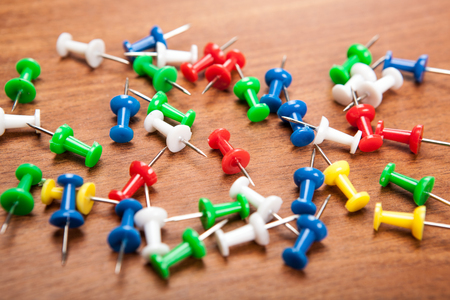 Set of push pins in different colors on a wooden background
