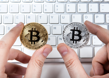 keyboard and two coins of bitcoin in the hand of a man close upの写真素材