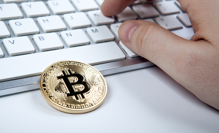 one golden coin of bitcoin and human hand on laptop keyboard close upの写真素材