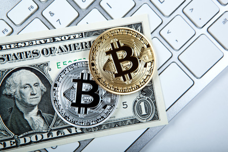 two coins of bitcoin and a dollar bill on the keyboard close upの写真素材