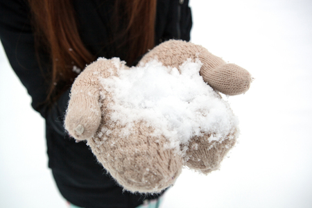 girl holding a pile of snow in her hands close upの写真素材