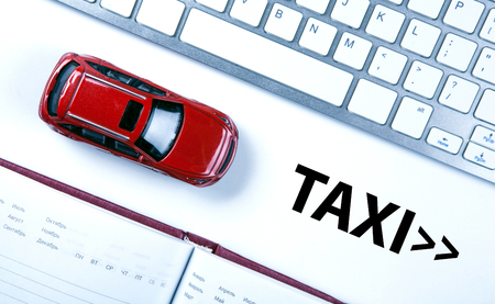red car model near the keyboard on the desktop and the inscription of a taxiの写真素材