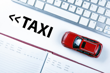 red car model near the keyboard on the desktop and the inscription of a taxiの写真素材