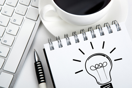 notebook with an icon of idea and keyboard and cup of coffee on the desktop closeupの写真素材