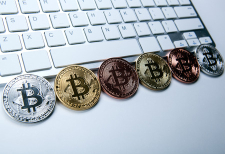 Six coins of bitcoin on white laptop pc keyboard closeupの写真素材