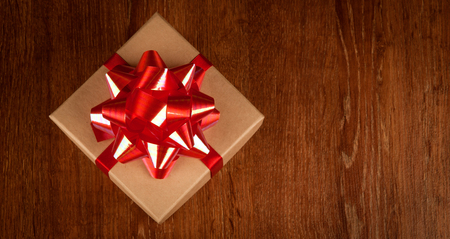 One festive gift box with a red bow on a wooden table view from aboveの写真素材