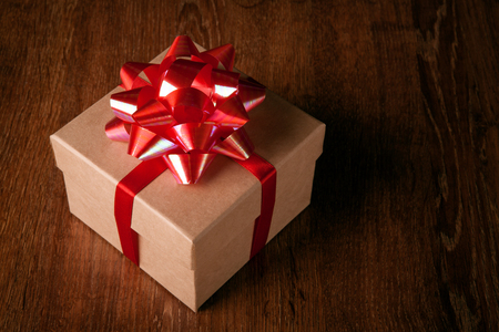 One festive gift box with a red bow on a wooden tableの写真素材