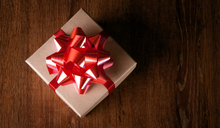 One festive gift box with a red bow on a wooden table view from aboveの写真素材