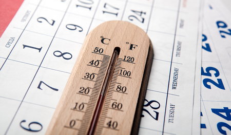 wall thermometer on white table on sheets of the wall calendar closeupの写真素材