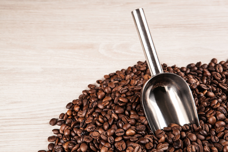 roasted coffee beans with scoop on a wooden background close upの写真素材
