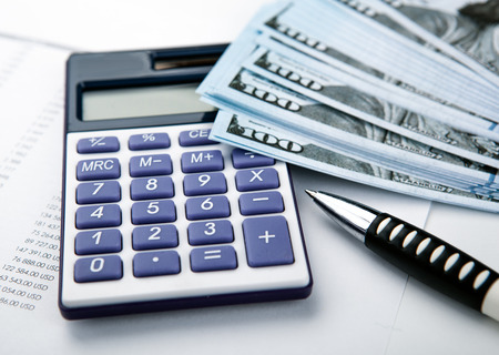 business still-life from a calculator and a bundle of banknotes 100 dollars close upの写真素材