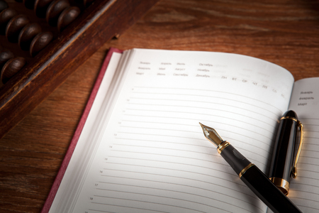fountain pen and diary on a table with an abacus close upの写真素材