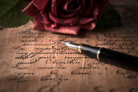 fountain pen on letter with text and red rose close up