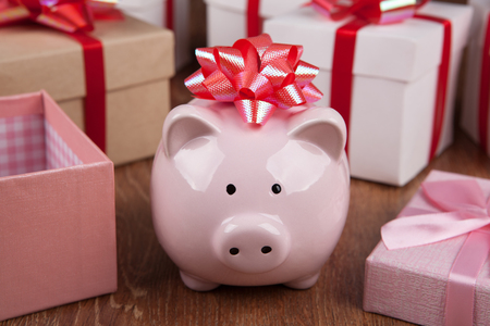 pink piggy bank with red bow against the background of gift boxes close upの写真素材