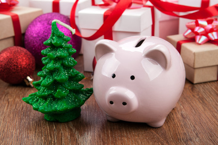 piggy bank with a Christmas tree against the background of Christmas toys and gift boxesの写真素材