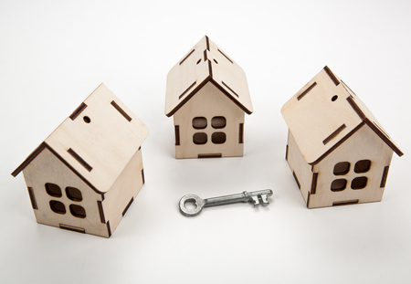 three wooden miniature houses and a door key on a white background close upの写真素材