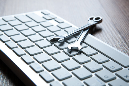 two wrenches and a computer keyboard close up concept