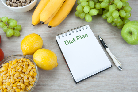 notebook with a diet plan with fresh vegetables and fruits on the table close upの写真素材