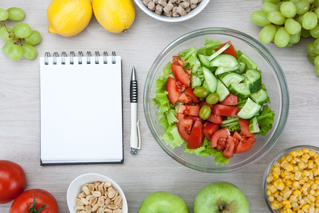 notebook with a diet plan with fresh vegetables and fruits and a side dish on the table top viewの写真素材