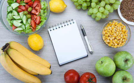 notebook with a diet plan with fresh vegetables and fruits on the table top viewの写真素材