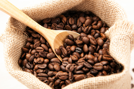 wooden spoon in the bag with roasted coffee beans close upの写真素材