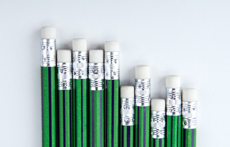 many simple pencils with green skin in a row on a white table top viewの写真素材