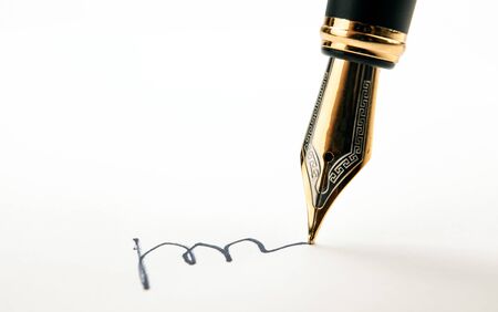 golden fountain pen leaves a signature on a white paper closeupの写真素材