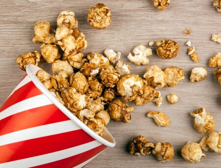 red cardboard cup with sprinkled sugar popcorn on a wooden table top viewの写真素材