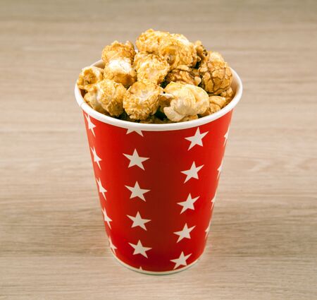 red cardboard cup with sugar popcorn on a wooden table close upの写真素材