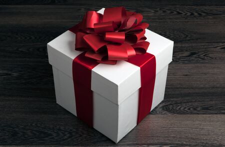 white box with red bow on a wooden tableの写真素材
